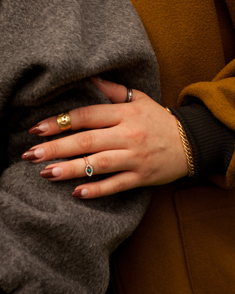 Close up photo of a models hand holding another models arm. They are wearing the House of Glass winter coats