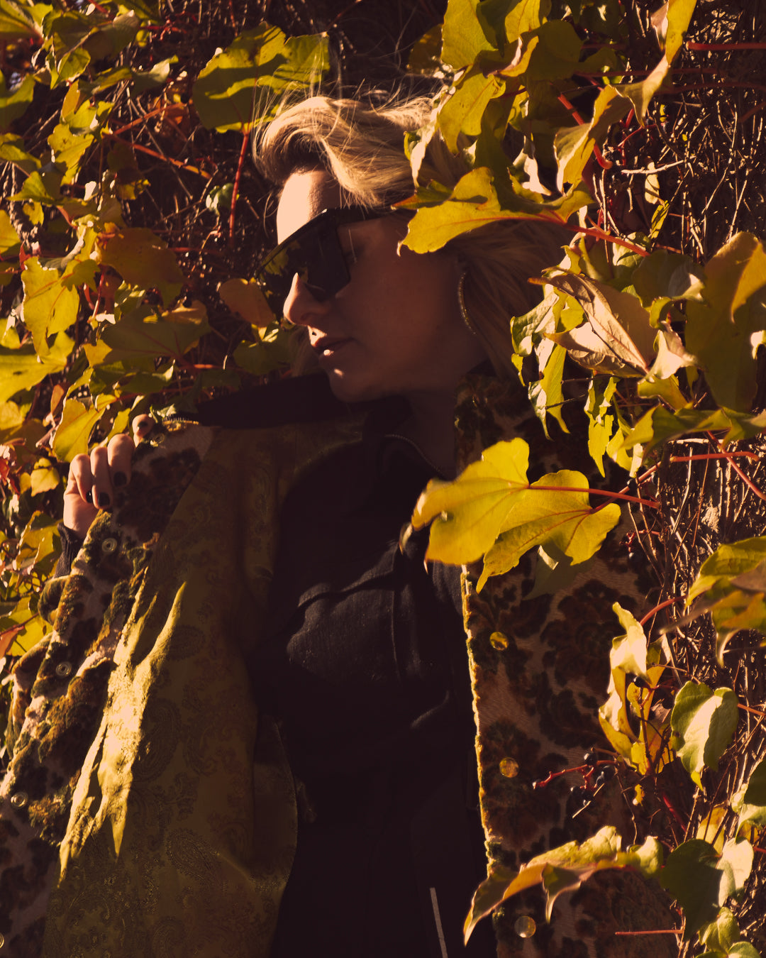 Photo of female model standing amongst some ivy wearing the House of Glass Carpetbag Bomber Jacket