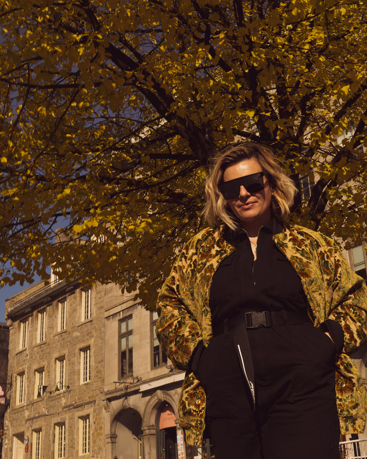 Photo of female model wearing the House of Glass Carpetbag Bomber Jacket standing in front of a fall tree