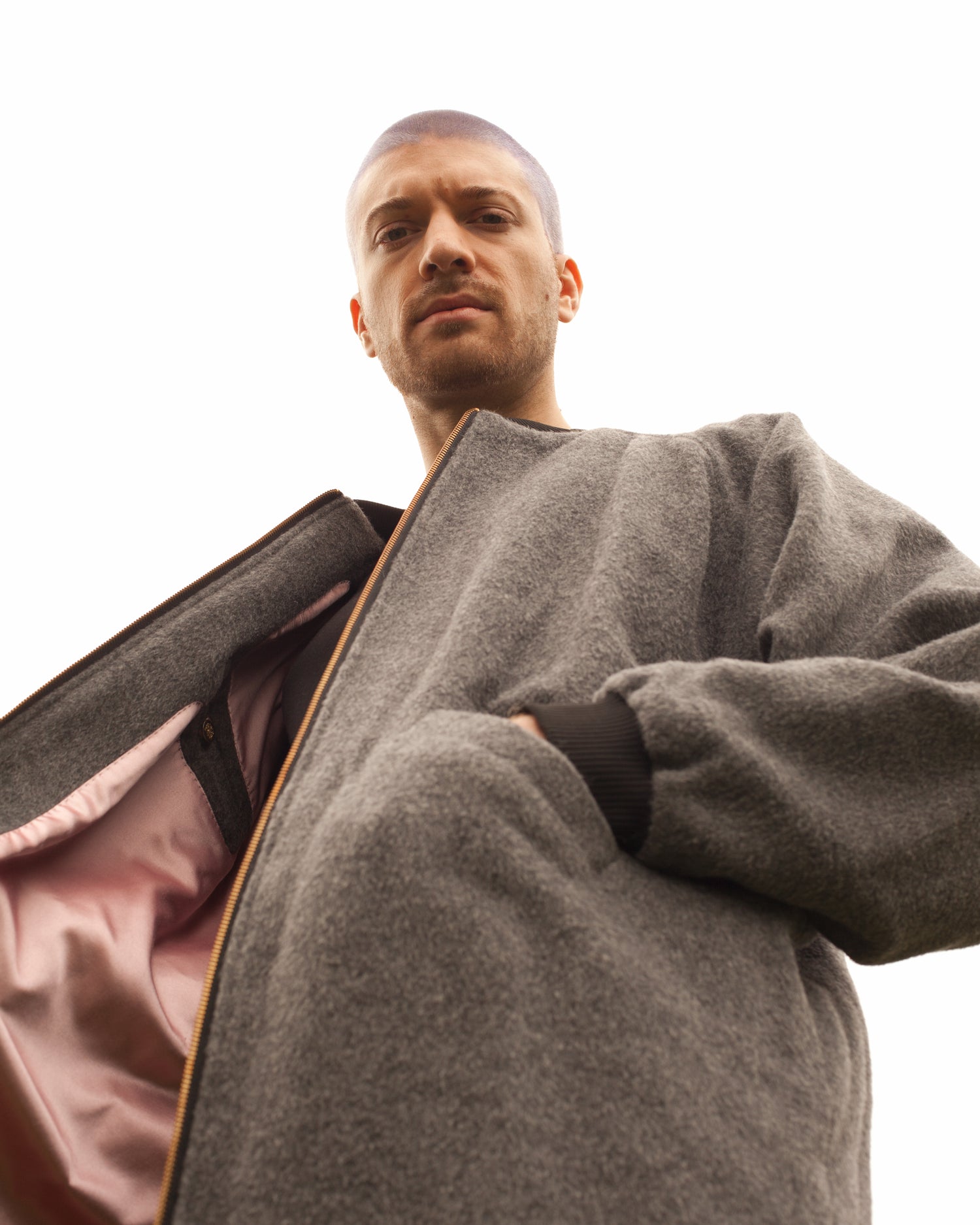 Picture of male model looking down into the camera wearing the House of Glass Luxe Winter Coat
