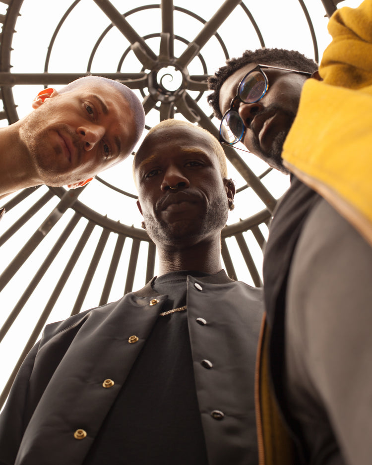 Picture of three male models looking down at the camera wearing the Boring Goth and Simples House of Glass coats