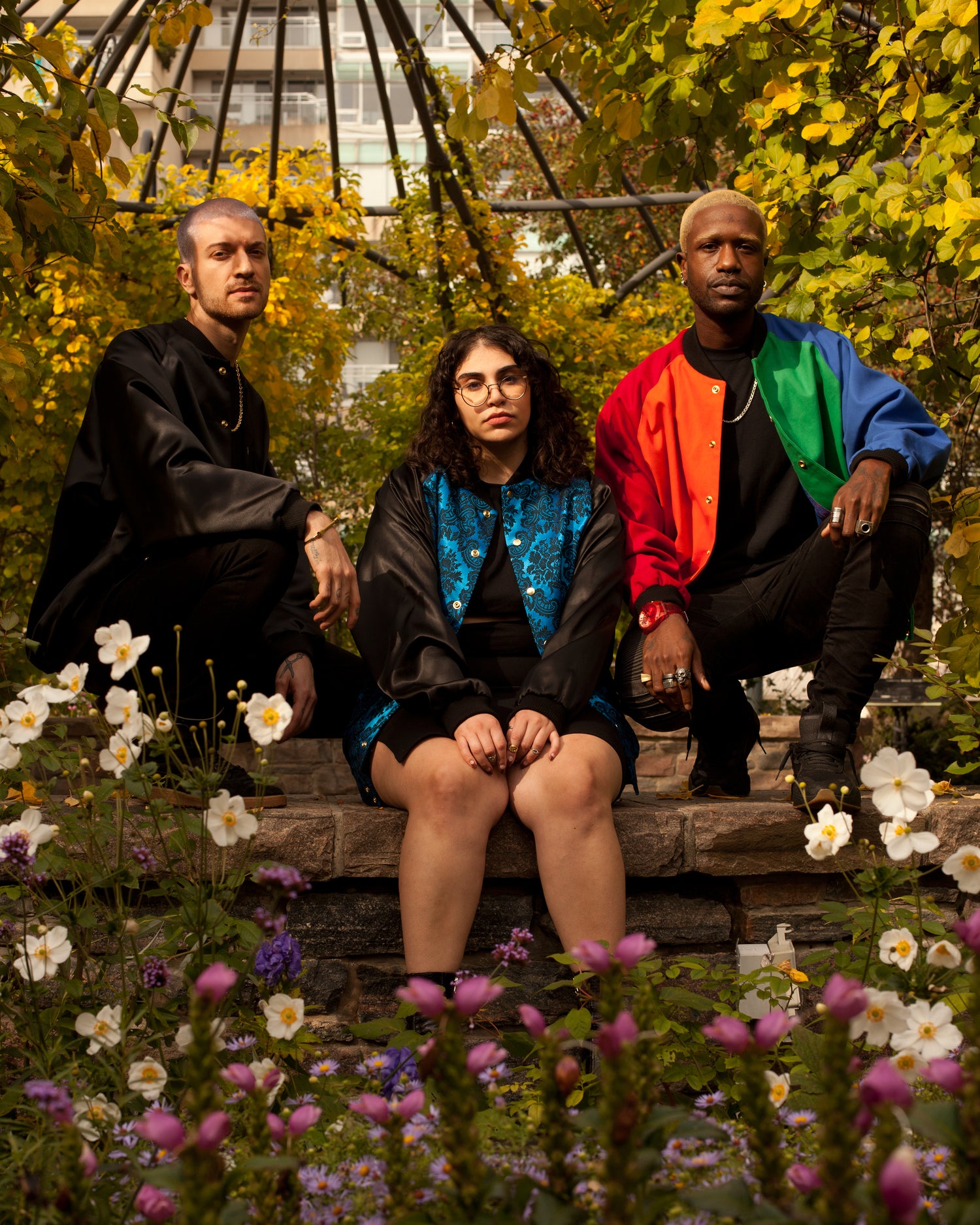 Picture of three models wearing different House of Glass garments and posing amidst fall leaves and flowers