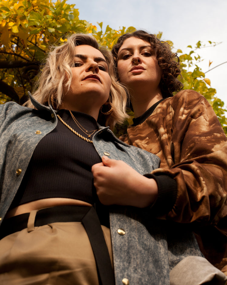 Picture of two models looking down into the camera. One is wearing the House of Glass Cardi B-omber Jacket and the other is wearing the House of Glass Dustbowl Sweater