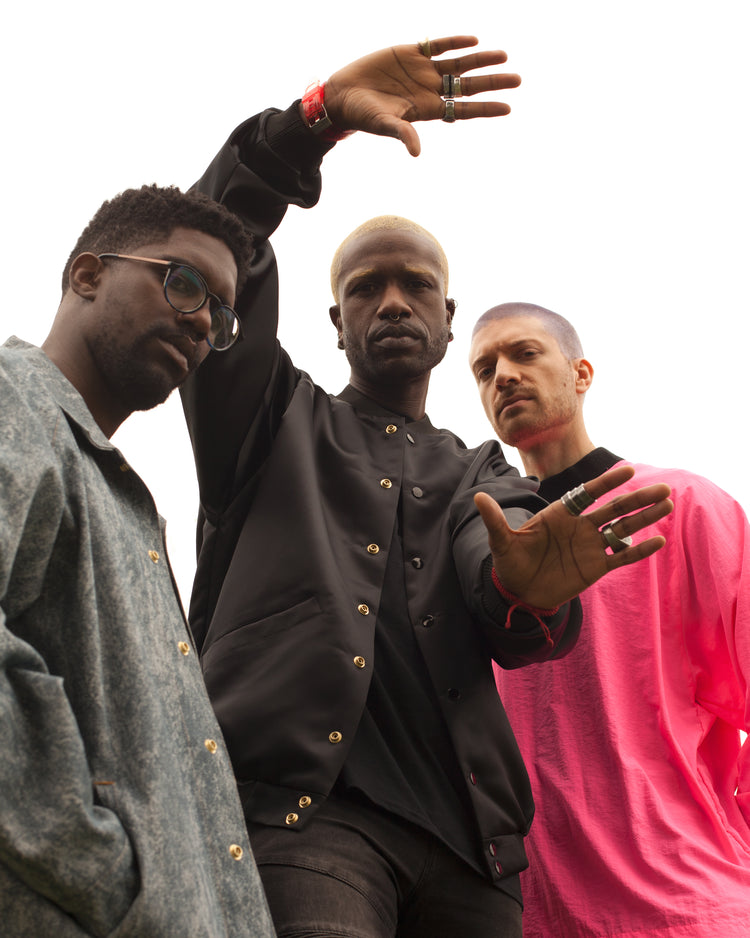 Three male models leaning into look into the camera. They are all wearing different House of Glass garments