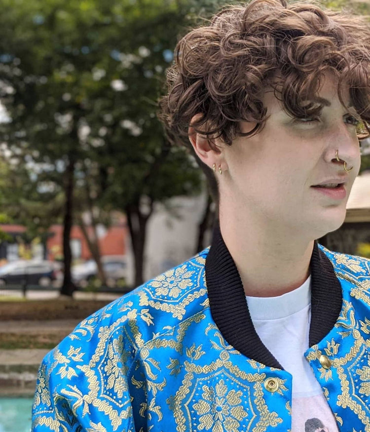 close up picture of non binary model standing in a swimming pool wearing the St Dimitar Bomber jacket