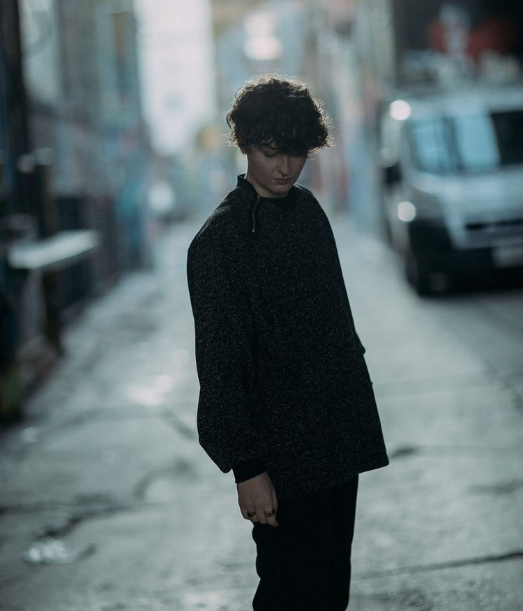 moody picture of non binary model wearing house of glass heathered cozy comfy sweater