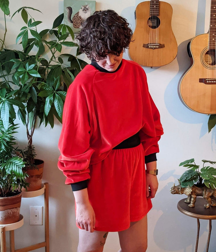 non binary model posing with plants and guitars wearing the tipping the velour halfsuit