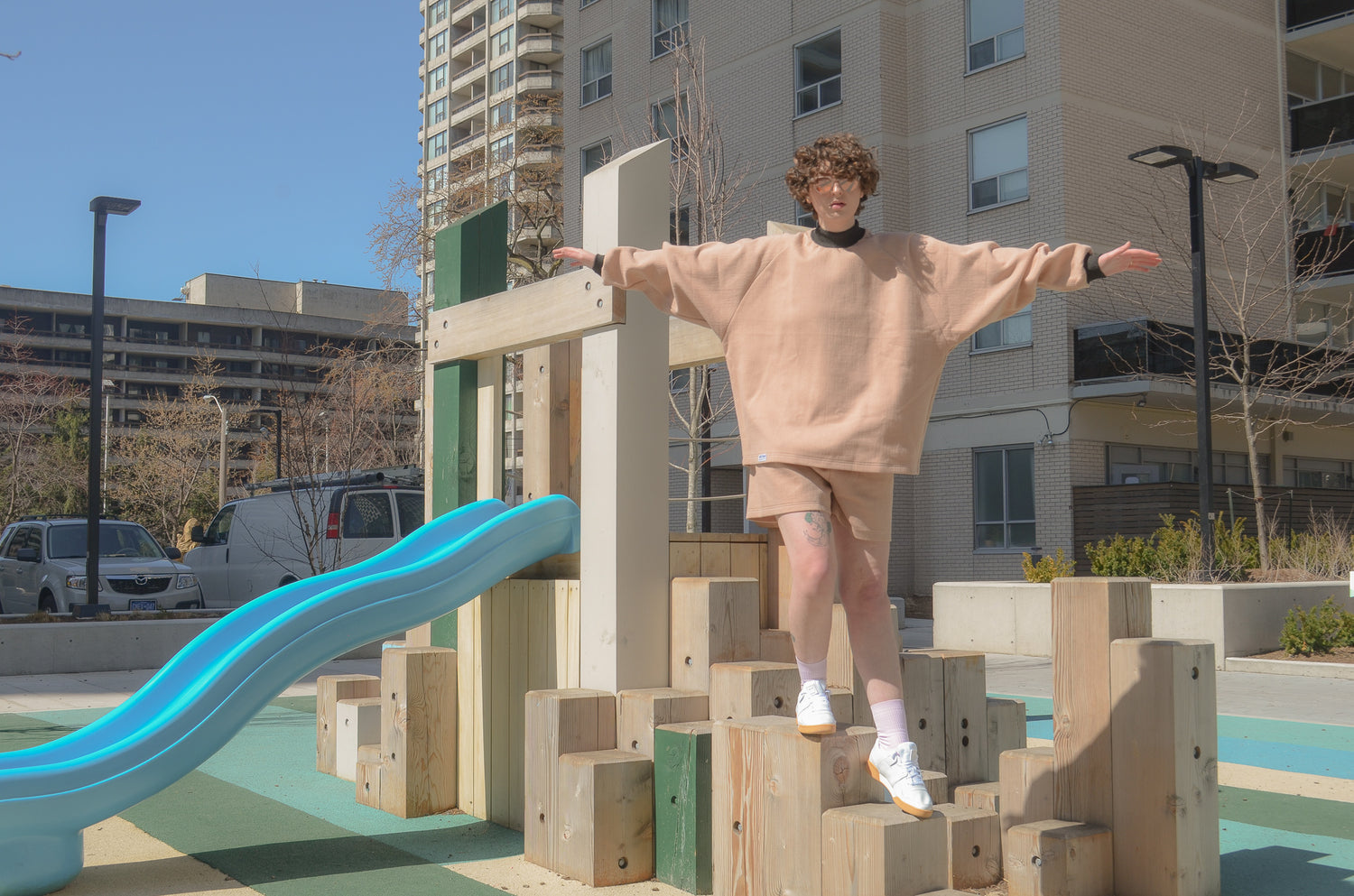 picture of non binary model playing on jungle gym wearing halfsuit in pink