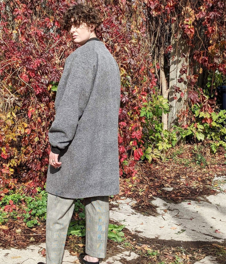 picture of non binary model wearing grey luxe winter coat with their back to the camera
