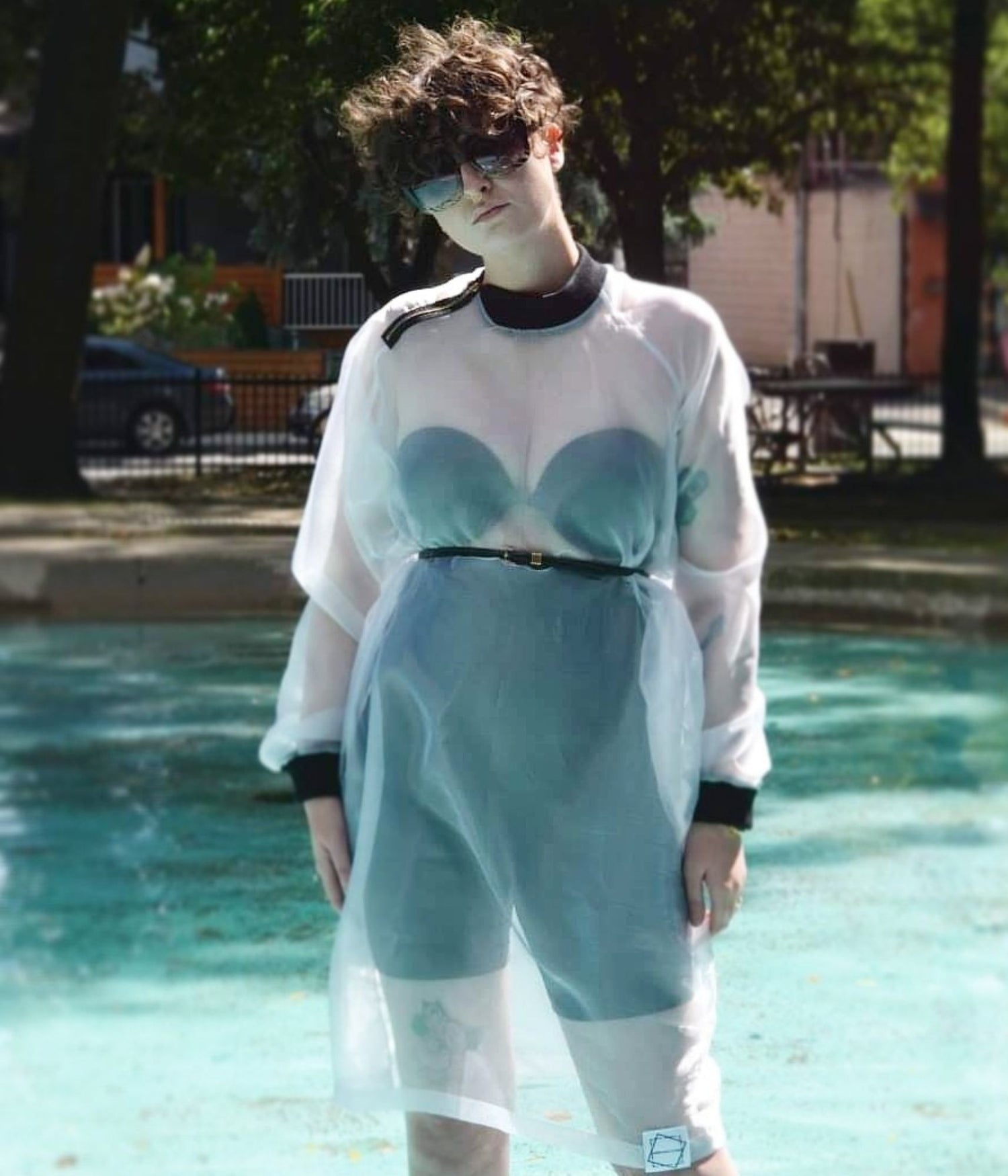 picture of non binary model wearing house of glass long white organza jumper standing in a swimming pool