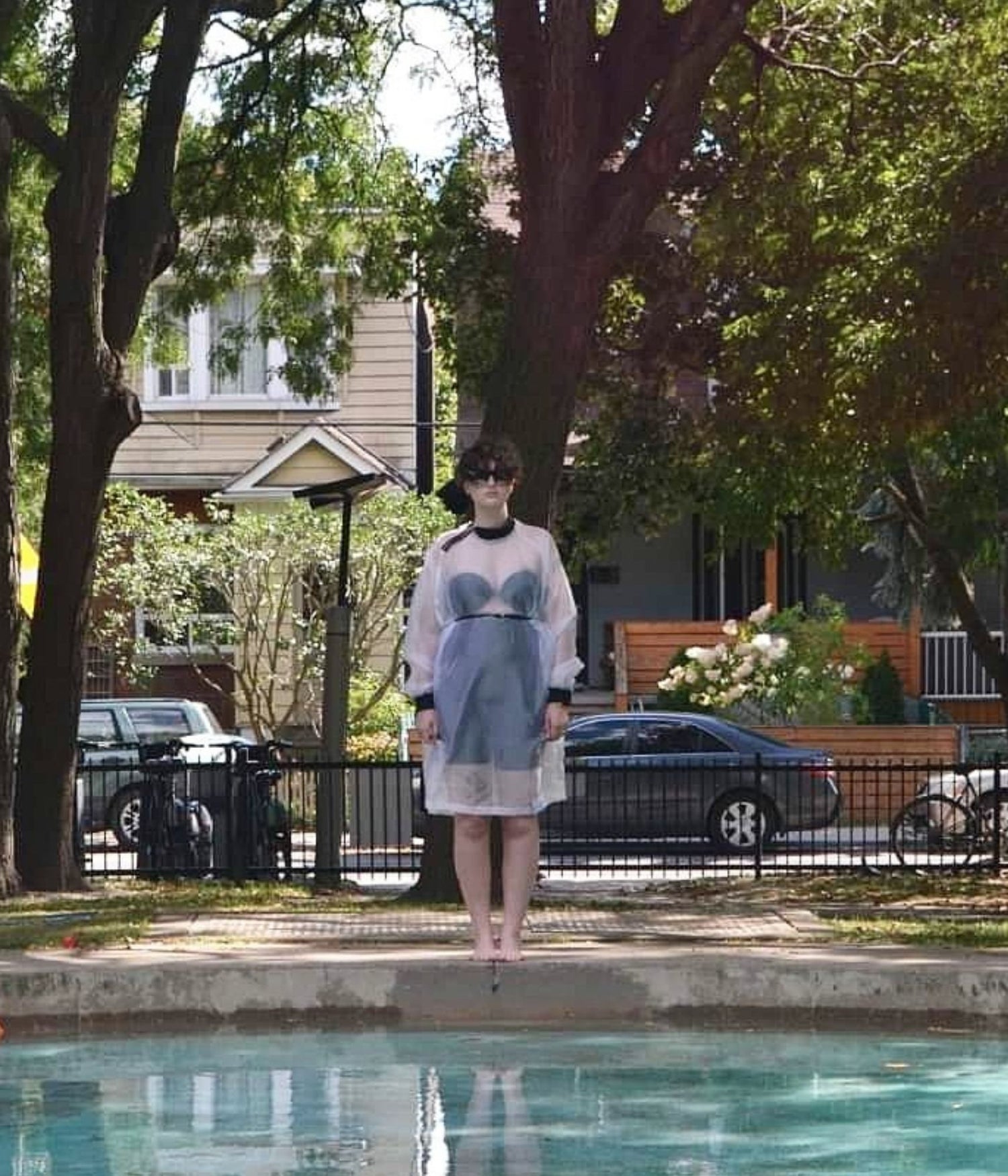 picture of non binary model wearing house of glass long white organza jumper standing on the edge of a swimming pool