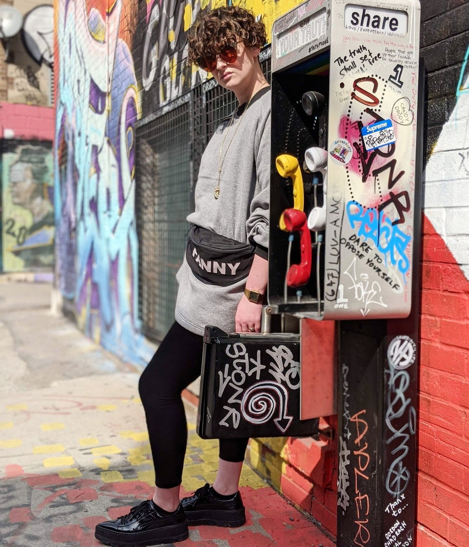 picture of non binary model wearing house of glass cozy comfy sweater in graffiti alley