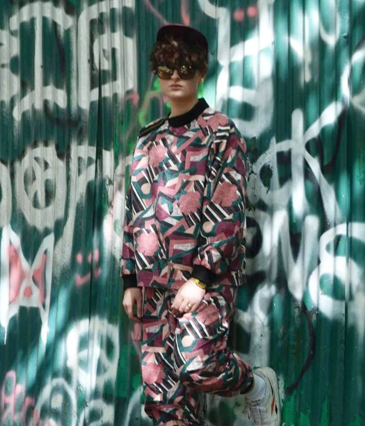 picture of non binary model wearing the St Kevin tracksuit in front of graffiti